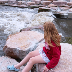 Girl sitting on a rock near a river